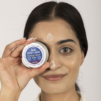 Woman holding Dewy Skin Natural Healing Tallow Balm and showing face application of the product
