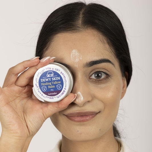 Woman holding Dewy Skin Natural Healing Tallow Balm and showing face application of the product